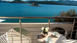 A balcony with a table set for two, overlooking a lake with a small island and mountains in the distance. - 1 bedroom awesome apartment in Klek (Klek)