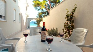 Una mesa con dos sillas, una botella de vino y dos copas de vino tinto.