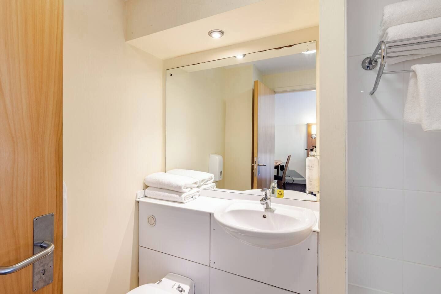 A modern bathroom with a white sink, mirror, and towel rack.