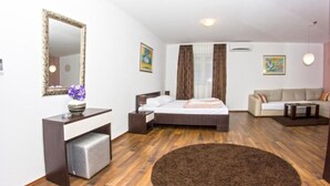 Moderni hotellihuone, jossa on sänky, sohva, työpöytä ja suuri peili.