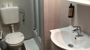 Kylpyhuone, jossa on wc, pesuallas ja suihkutila.