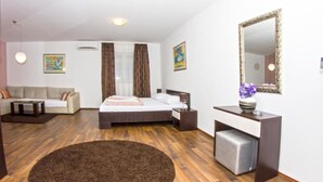 Moderni hotellihuone, jossa on sänky, sohva, työpöytä ja suuri peili.