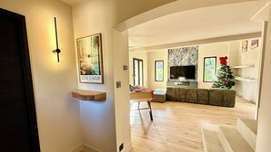 A modern living room with a wooden floor, a sofa, a television, and a small Christmas tree. - 🔥 NEW FOR RENT - Premium Villa with Pool & Games - 10 pers (Fréjus)