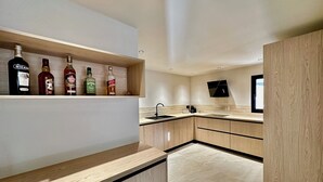 A modern kitchen with wooden cabinets, a marble countertop, and a built-in shelf with liquor bottles. - 🔥 NEW FOR RENT - Premium Villa with Pool & Games - 10 pers (Fréjus)