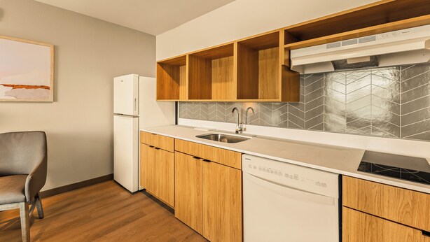 A modern kitchen with wooden cabinets, a built-in dishwasher, and a stainless steel sink. - LivAway Suites Austin San Marcos (San Marcos)