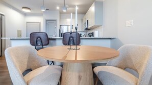 Eine moderne Küche mit weißen Schränken, einem runden Holztisch und zwei Stühlen.