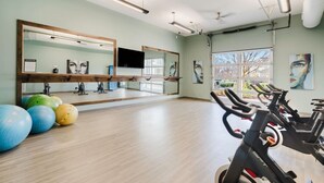 Un gimnasio con equipo de ejercicio, grandes espejos y vistas al exterior.