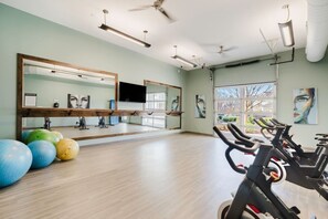 A gym with exercise equipment, large mirrors, and a view of the outdoors. - Bright, Cozy 3BD Apt w/ Pool + Gym (Matthews)