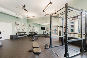 A gym with exercise equipment, benches, and a mirrored wall. - Bright, Cozy 3BD Apt w/ Pool + Gym (Matthews)