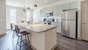 Una cocina moderna con una isla central, electrodomésticos de acero inoxidable e iluminación colgante.