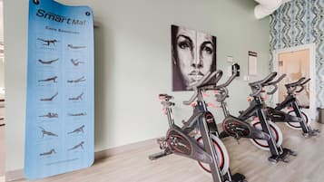 A fitness area with exercise bikes and a SmartMat poster displaying core exercises.