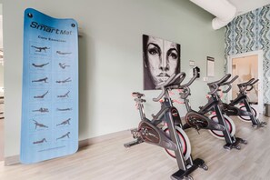 A fitness area with exercise bikes and a SmartMat poster displaying core exercises.