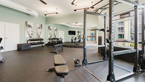 Un gimnasio con equipo de ejercicio, bancos y un espejo grande.