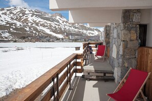 Un balcon avec des balustrades en bois, un mur en pierre et une chaise rouge.