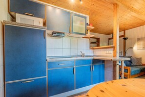 A compact kitchen with blue cabinets, a microwave, and a sink. - Binzer Waldhof - Haus Fuchsbau (Binz)