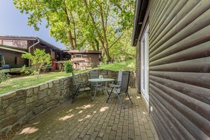 A patio with a table and chairs, a stone wall, and a wooden building with horizontal siding. - Binzer Waldhof - Haus Fuchsbau (Binz)