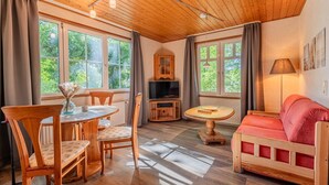 A cozy room with wooden furniture, a TV, and large windows. - Binzer Waldhof - Igelhaus (Binz)