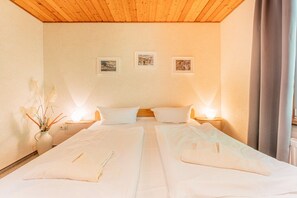 A double bed with white linens, two bedside tables, and wall-mounted lamps. - Binzer Waldhof - Igelhaus (Binz)