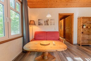 A room with a wooden table, red sofa, and a wooden cabinet.