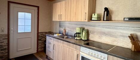 A modern kitchen with wooden cabinets, a built-in oven, and a coffee maker.