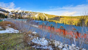 A row of red buildings with blue roofs, surrounded by snow-covered ground and trees. - Walk to Chair Lift: Mtn-View Schweitzer Studio! (Sandpoint)