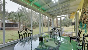 A glass-enclosed dining area with a round table, chairs, and a view of the outdoors. - Hawthorne Angler's Cabin w/ Lake + Dock Access! (Hawthorne)