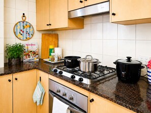 Eine Küche mit Holzausstattung, einem Gasherd, einer Dunstabzugshaube und einer Arbeitsplatte mit Pflanze und Zeitschrift.