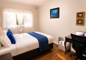 Un dormitorio con cama, escritorio y radiador.