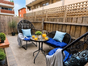 A patio with a round table, two chairs, a sofa, and a wooden fence. - A Little Home close to Beach & F1 withPrivate Courtyard Free Parking, Ground fl (St Kilda)
