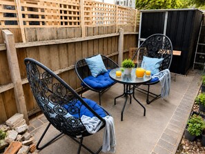 A patio area with two chairs, a table, and a small garden. - Audrey Apartment near to Beach/ F1 with Courtyard and Free Secure Parking (St Kilda)