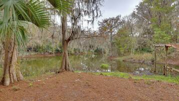 A natural landscape with a pond, trees, and a wooden structure.
