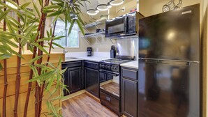 A modern kitchen with dark cabinetry, a stainless steel refrigerator, a microwave, and a stove. There is a plant in the corner and a window providing natural light. - Bass Fishing Paradise w/ Shared Dock in Hawthorne! (Hawthorne)