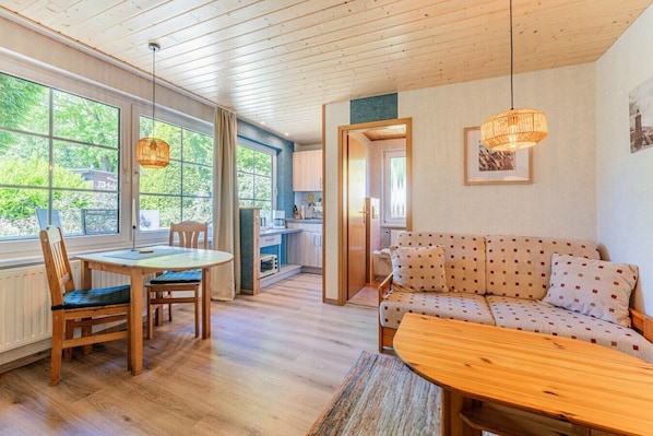A cozy room with a wooden dining table, a sofa, and a kitchen area.