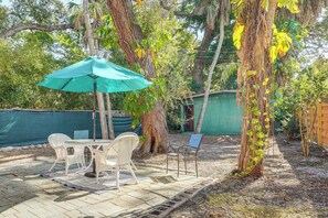 An outdoor patio with a table and chairs, a green umbrella, and a wooden deck. - 5 Mi to St Pete Beach! Snowbird Home w/ Large Yard (St. Petersburg)