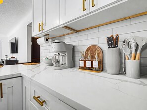 Eine moderne Küche mit weißen Schränken, einer Kaffeemaschine und einem Holzschneidebrett.