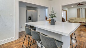A modern kitchen with a large island, bar stools, and a small potted plant. - Walk to Marshall University: Home w/ Private Yard! (Huntington)