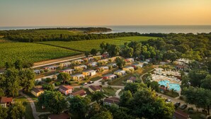 Un complex turístic costaner amb diverses allotjaments de tipus bungalows, una piscina central i vistes àmplies del mar i la vegetació circumdant.