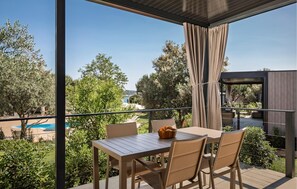 A balcony with a table and chairs, overlooking a pool and greenery. - Stunning home in Novigrad with swimming pool (Novigrad)