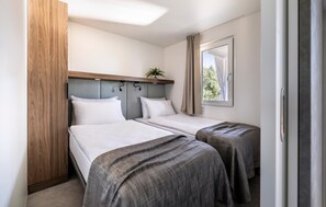 A hotel room with two beds, a wooden headboard, a small plant, and a window with curtains. - Stunning home in Novigrad with swimming pool (Novigrad)