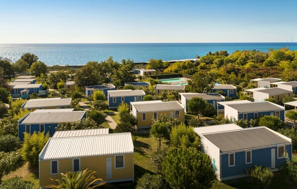 A row of compact, single-story mobile homes with a flat roof, arranged in a dense cluster with a view of the sea in the background. - Awesome home in Novigrad with swimming pool (Novigrad)