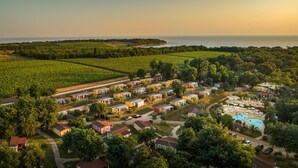 Ein Küstenresort mit mehreren Bungalows, einem zentralen Pool und Meerblick.