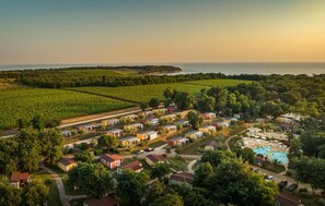 Ein Küstenresort mit mehreren Bungalows, einem zentralen Pool und Meerblick.
