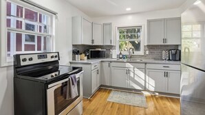 A modern kitchen with white cabinets, stainless steel appliances, and a view of the outside. - Church Street Retreat - Downtown Location! (Wisconsin Dells)