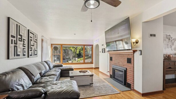 A modern living room with a leather sofa, a fireplace, and a large TV. - Church Street Retreat - Downtown Location! (Wisconsin Dells)