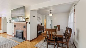 A dining area with a brick fireplace, wooden dining table, and chairs. - Church Street Retreat - Downtown Location! (Wisconsin Dells)