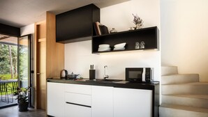 A modern kitchen with a built-in microwave, a kettle, and a sink. There is a staircase to the right and a door leading to a balcony with a view of trees. - Lovely home in Njivice with swimming pool (Njivice)