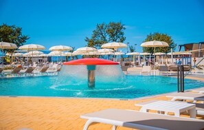 A pool area with multiple lounge chairs and umbrellas, a water feature, and a clear blue sky. - Awesome home in Njivice with WiFi (Njivice)