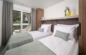 A hotel room with two beds, a balcony with a chair, and a shelf with decorative items. - Awesome home in Njivice with WiFi (Njivice)