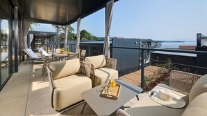 A covered outdoor seating area with a sofa, chairs, and a table, overlooking a body of water. - Gorgeous home in Njivice with WiFi (Njivice)