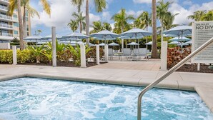 A pool area with a hot tub, umbrellas, lounge chairs, and a sign listing spa rules. - 12/21-26 Marriott Luxury 2-BR Beach Villa - Marco Island Resort - Crystal Shores (Marco Island)